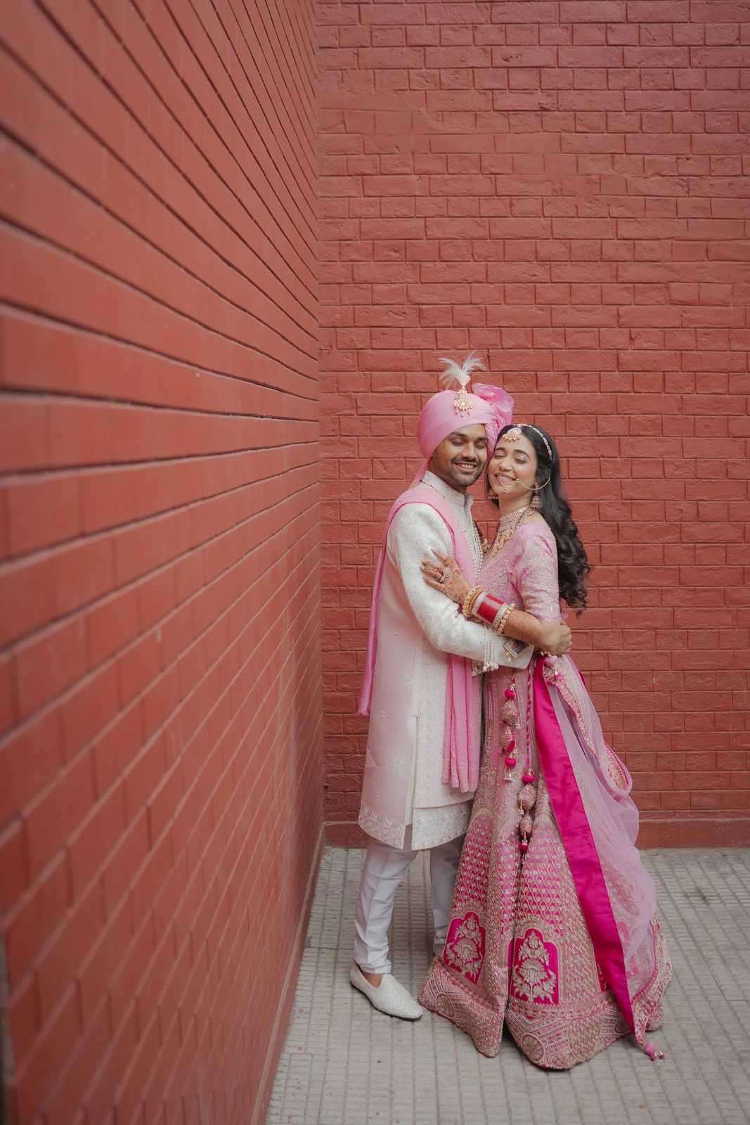 Bride and Groom Standing Together Against Pink Backdrop