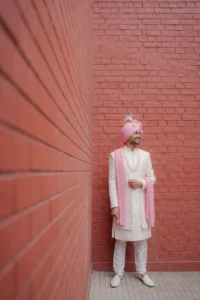 Elegant Groom Standing Against Pink Backdrop