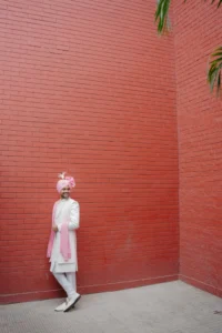 Groom Portrait Against Terracotta Wedding Backdrop