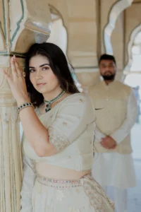 Close-up of bride leaning against a pillar, groom beside her