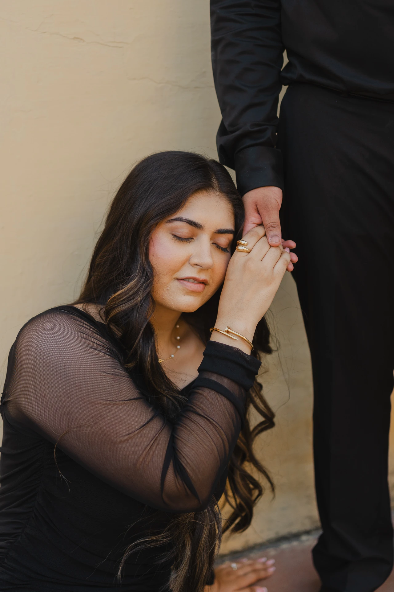 Close-up of woman leaning against a stone wall, black dress