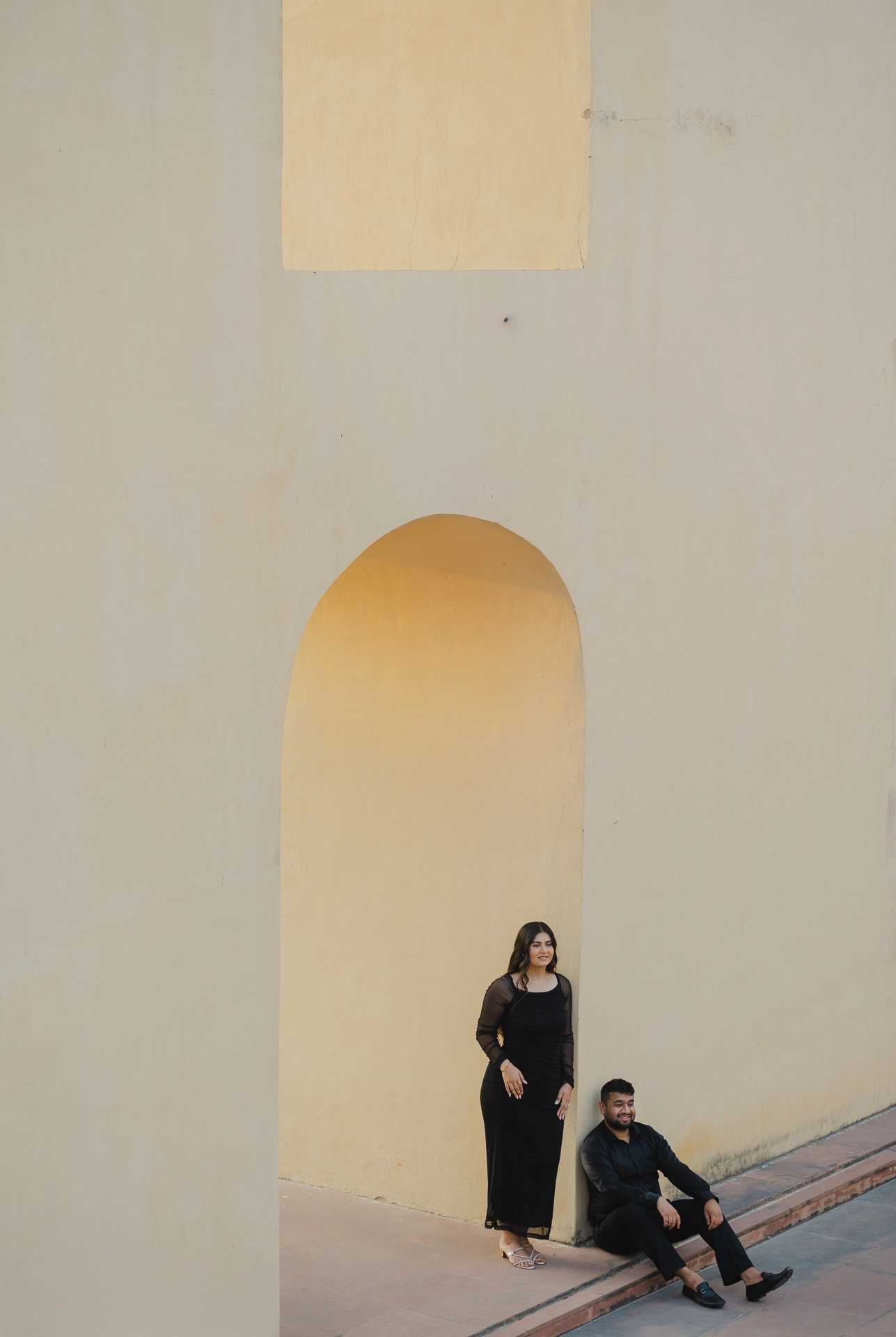 Couple standing beneath a stone archway, black outfits