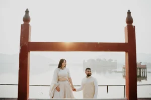 Couple standing beneath a wooden frame overlooking water, Jaipur