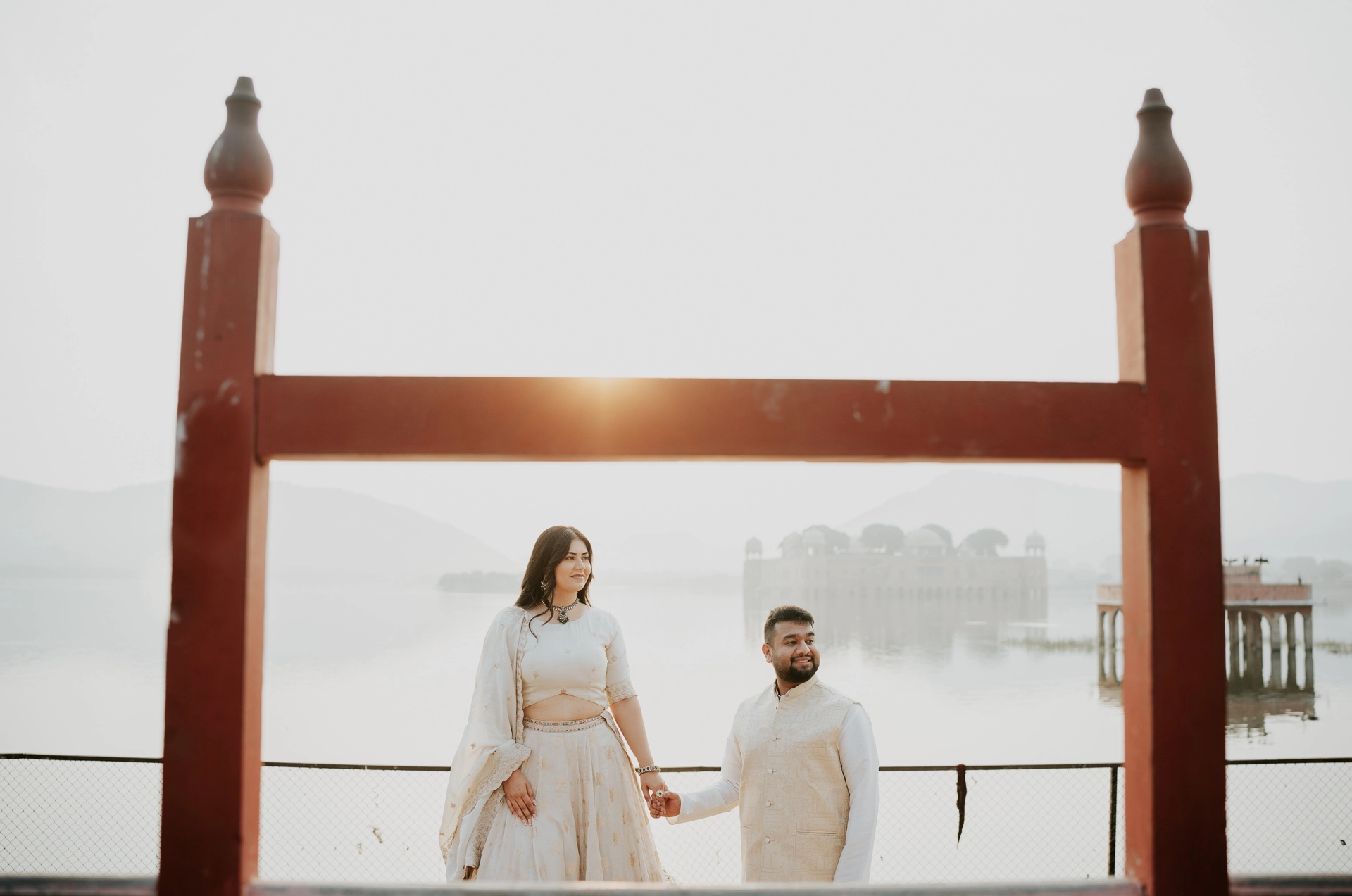Couple standing beneath a wooden frame overlooking water, Jaipur