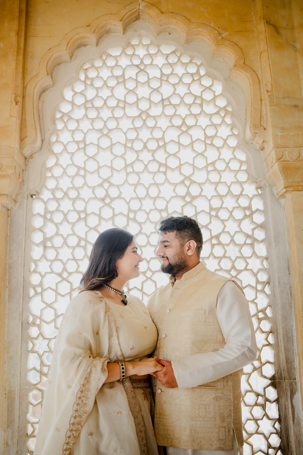 Couple standing close inside a carved stone window frame