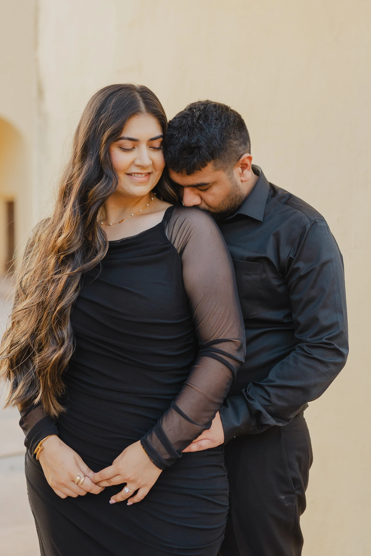Couple standing close together, both in black attire