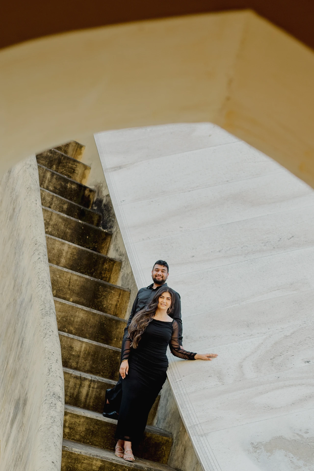 Couple standing on a stone staircase, black outfits