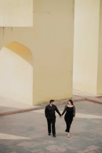 Couple standing together beneath a stone archway, black attire