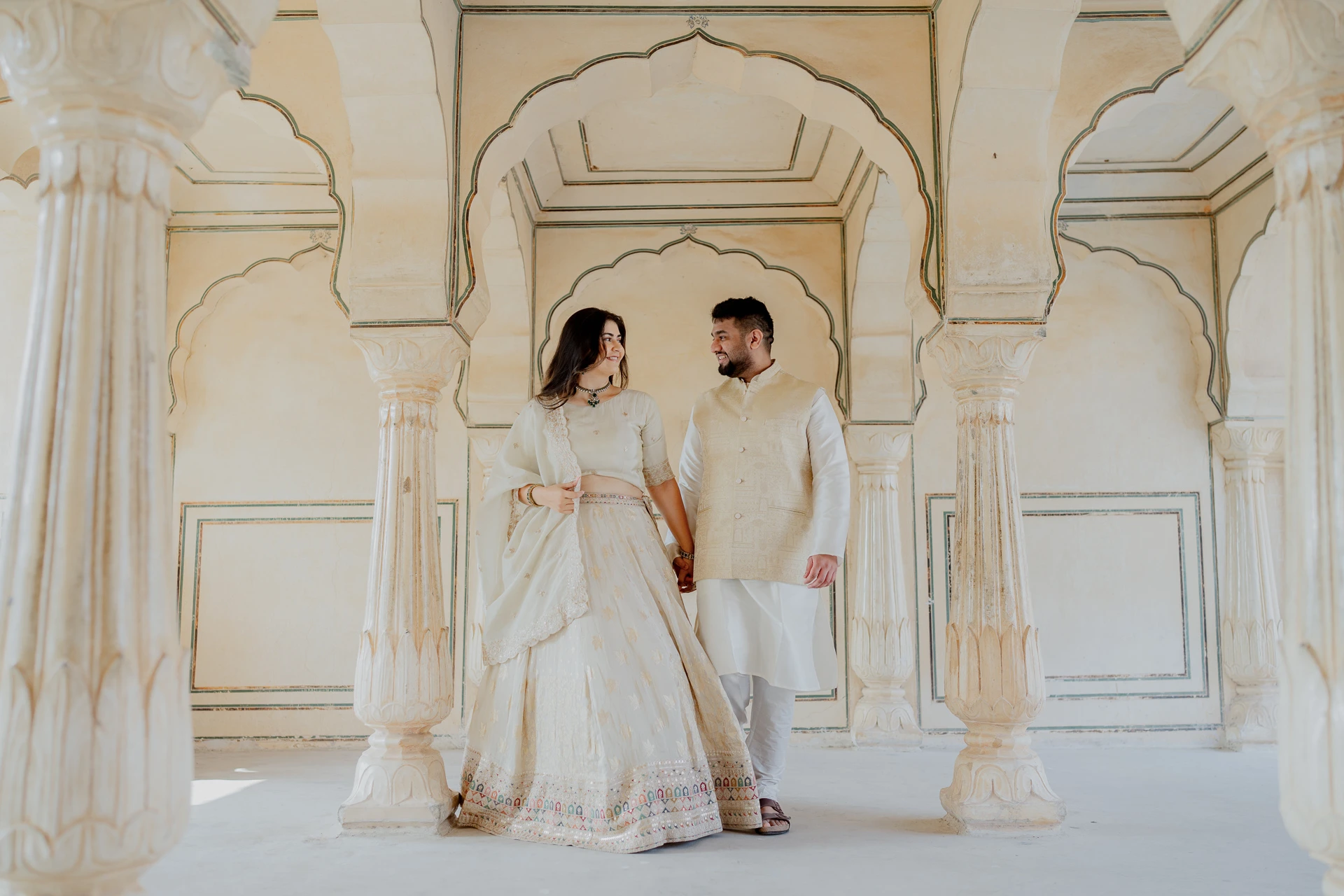 Couple standing together in an arched sandstone hall, Amer Fort