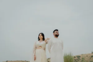 Couple standing together in white outfits on sand, Jaipur
