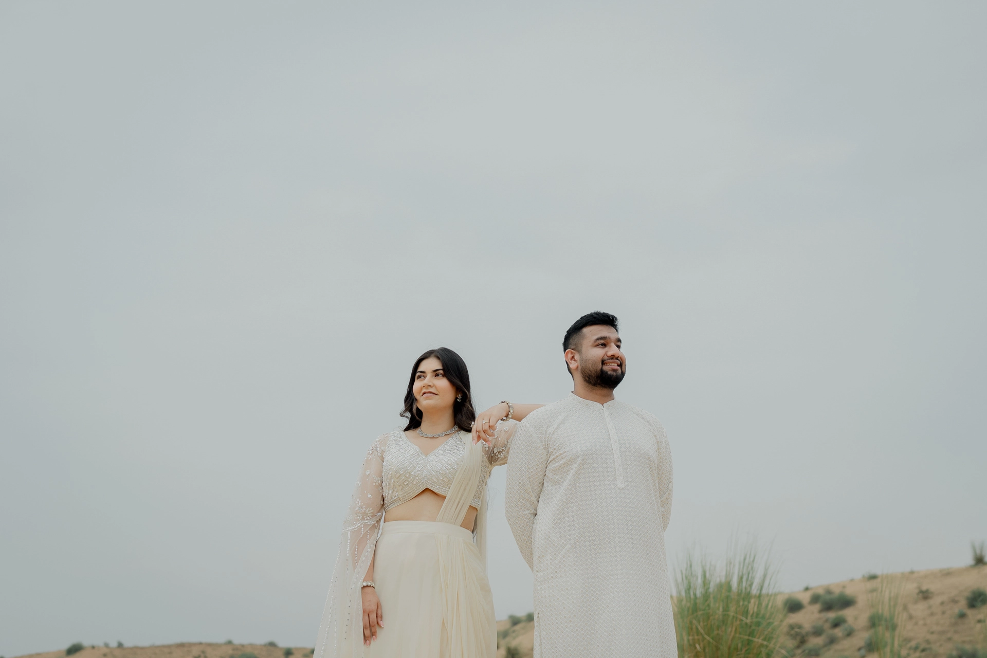 Couple standing together in white outfits on sand, Jaipur