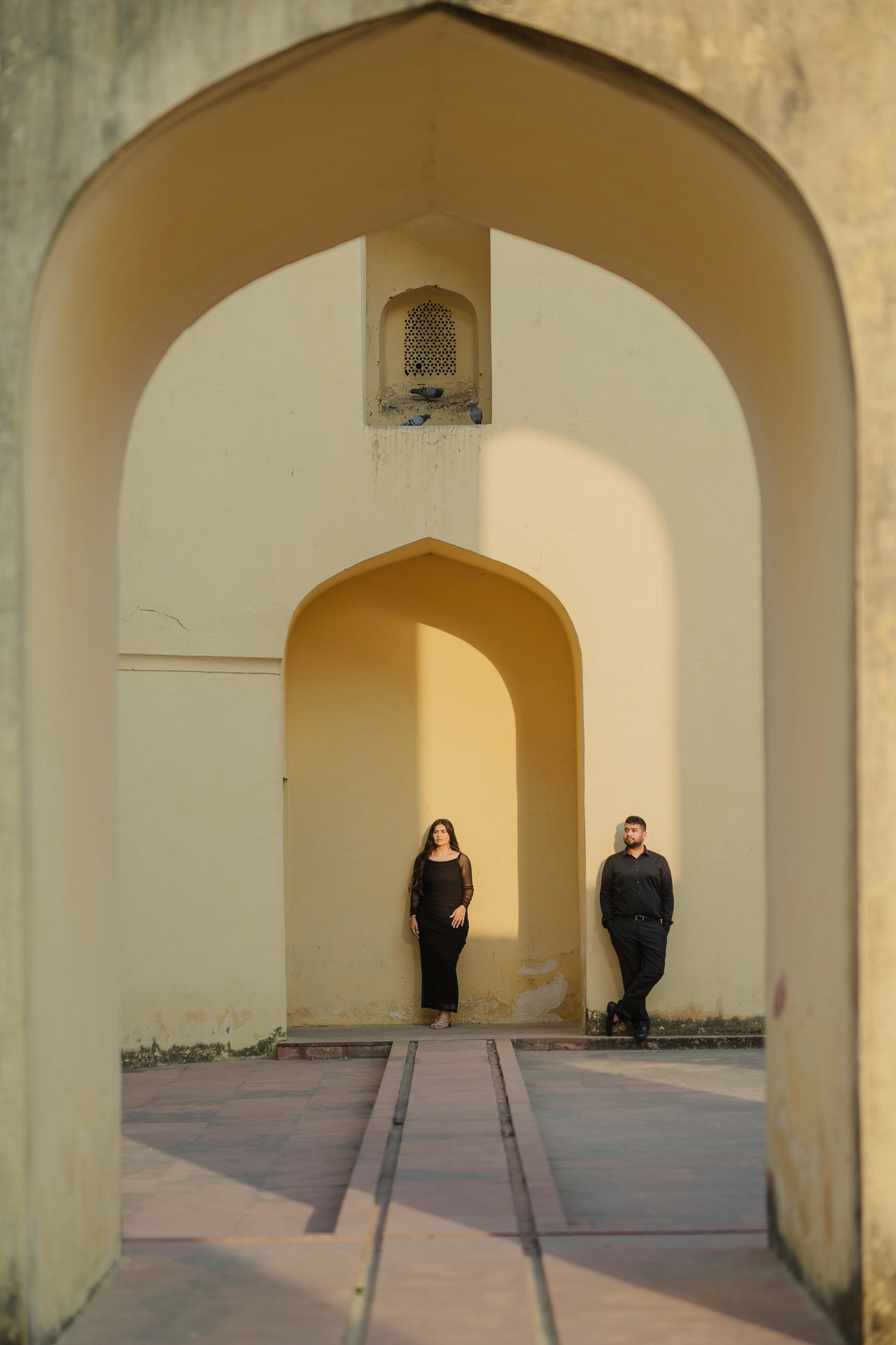 Couple standing under twin stone arches at Jantar Mantar