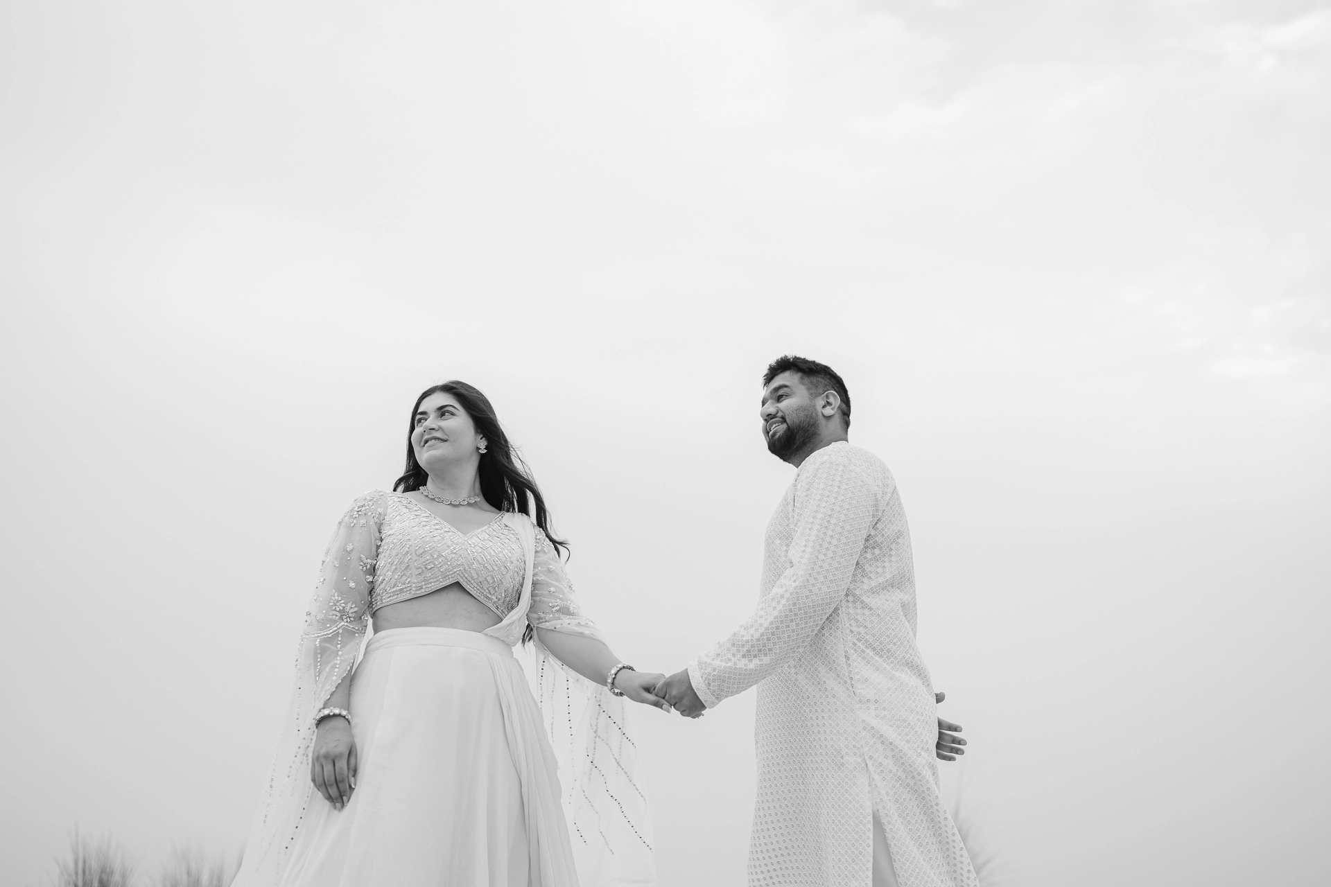 Couple walking hand in hand on sand dunes