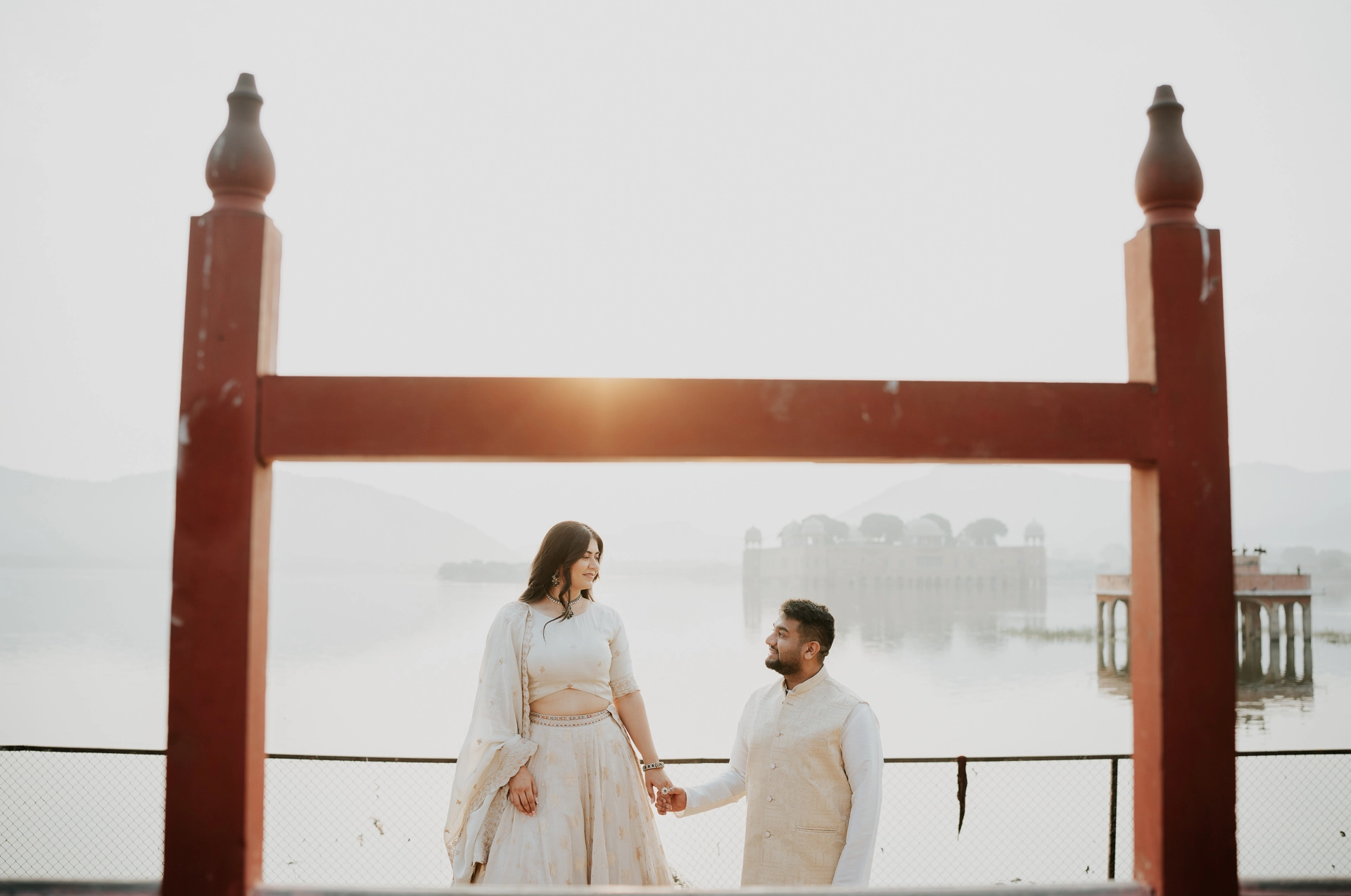 Couple walking under a rustic wooden arch by the lake
