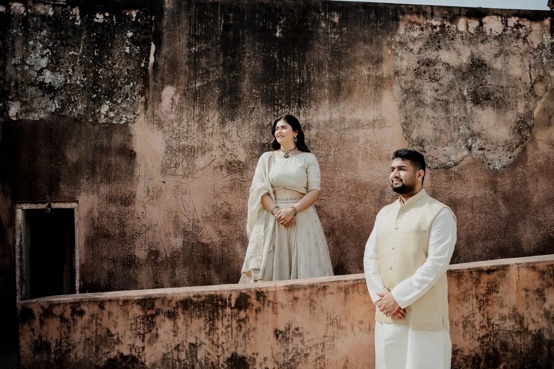 Sepia-toned photo of couple against a textured fort wall