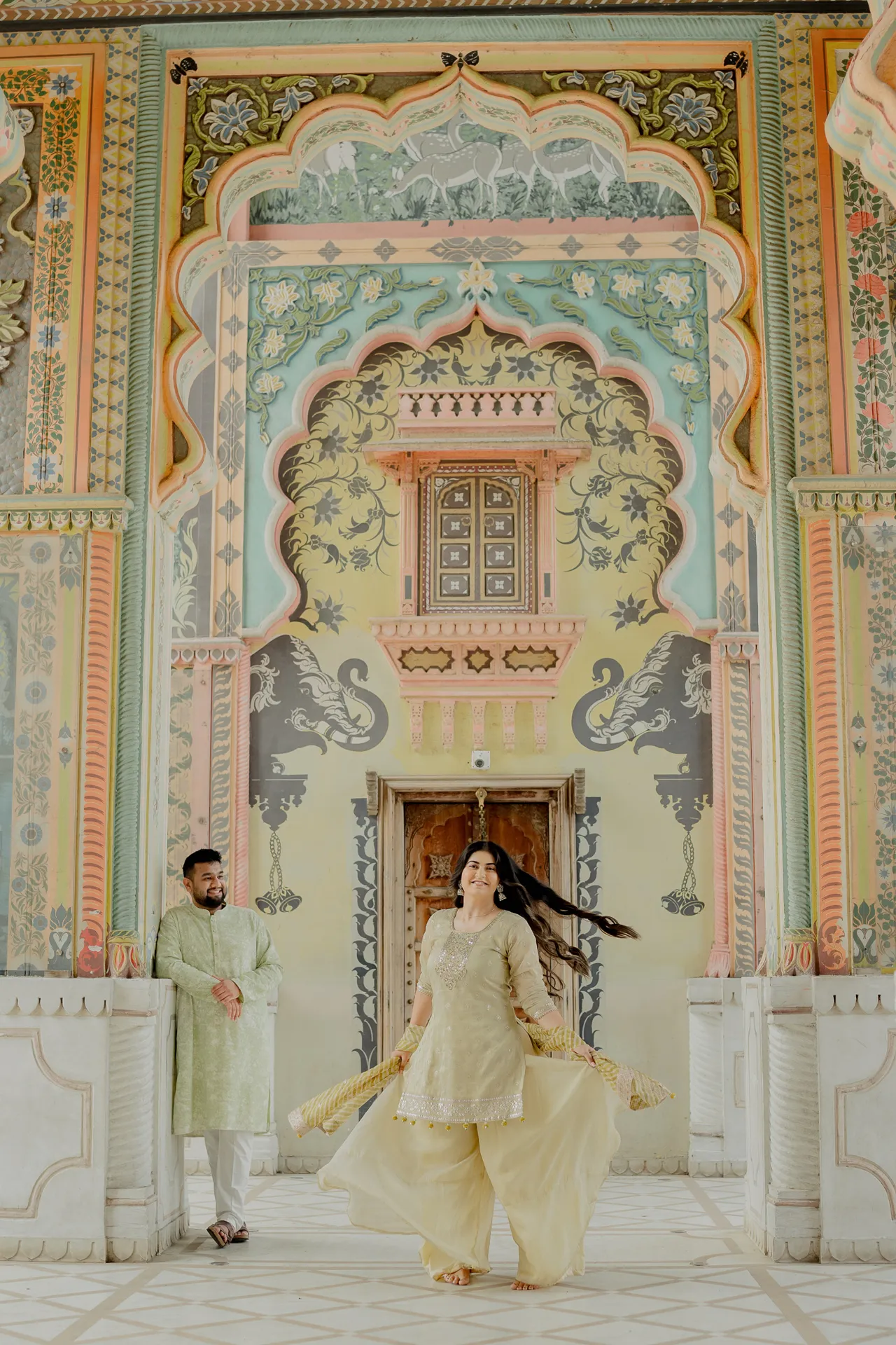 Woman standing alone under a painted gateway, Jaipur